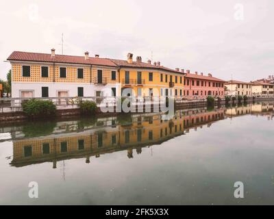 Pittoresche case colorate a Gaggiano, riflesse nel canale navigabile chiamato Naviglio Grande, vicino a Milano. Lombardia, Italia. Foto Stock