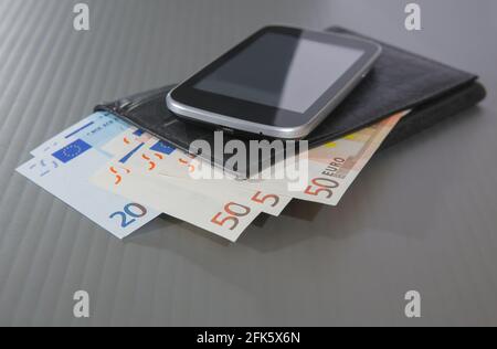 Di banconote in euro in borsa e lo smartphone su sfondo grigio Foto Stock