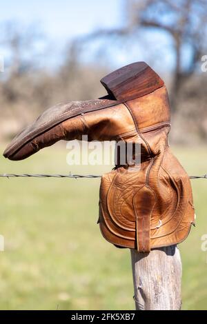 Vecchio stivale da cowboy appeso su una recinzione nel Texas Paese di collina Foto Stock