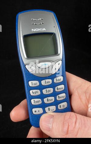 Un uomo che detiene un telefono Nokia 3210e arancione (il Nokia 3210e è stato originariamente rilasciato nel 1999), Foto Stock