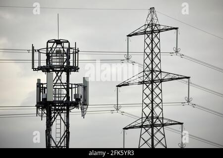 Primo piano di un palo di telefono della rete cellulare con silhouette e. traliccio elettrico torre pilone Foto Stock