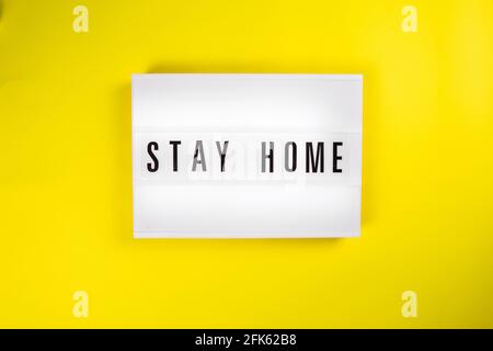 Lightbox con messaggio STAY HOME su sfondo giallo, focolaio di auto-isolamento Foto Stock