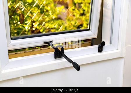 Finestra in alluminio con apertura verso l'esterno in una cucina. Cornice di colore bianco. Vista dall'interno. Foto Stock