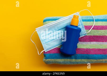 maschera protettiva e crema solare su una spiaggia di vacanza estiva asciugamano Foto Stock