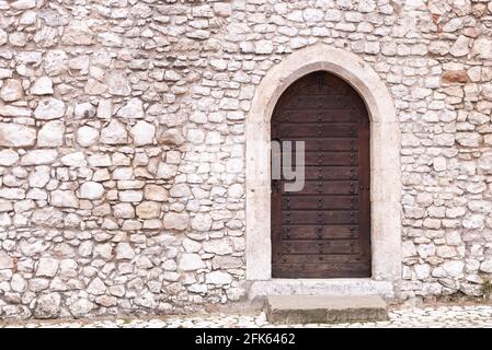 Muro di pietra con porta. Vecchia muratura e una vecchia porta di legno nel muro del castello. Torna all'ingresso di uno dei castelli di Cracovia. Foto Stock