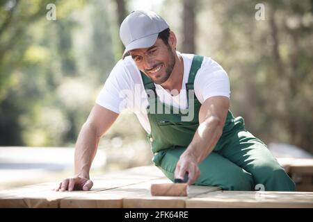 uomo in tute pittura vecchia panca nel parco Foto Stock