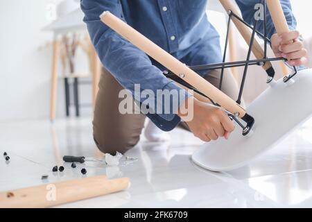 Giovane uomo che fa il lavoro fai da te, assemblando i mobili a casa. Foto Stock