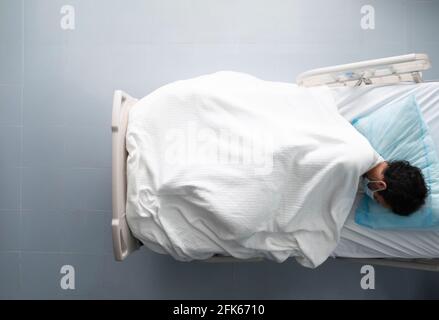 Giovane addormentato su un letto d'ospedale. Foto in alto. Foto Stock
