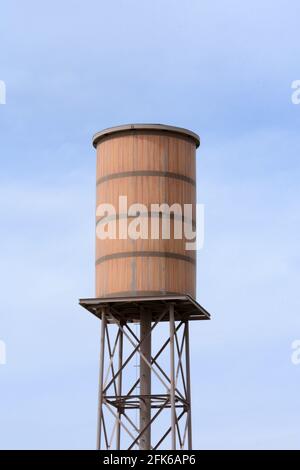 Torre d'acqua retrò in legno contro il cielo blu con nuvole chiare Foto Stock