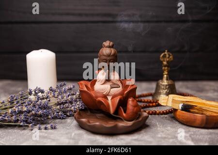 Statuetta di bastoni di incenso del Buddha sul posto di lavoro. Candelabro per incenso. Foto Stock