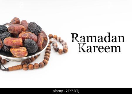 Testo RAMADAN KAREEM con date o frutta kurma e perle di rosario o Tasbih su sfondo bianco. Ramadan Kareem e concetto islamico Foto Stock
