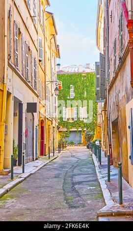 La stretta Rue Loubon, fiancheggiata da storici edifici in legno di scabvicino con una vista sul muro verde della casa, coperto di viti d'uva, Aix-en-provata Foto Stock