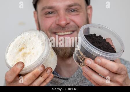 Norimberga, Germania. 19 Apr 2021. Ralph Haydl tiene i funghi per i funghi di ostrica e i terreni di caffè in una pentola di una coltura di funghi fissata in una mano (r) e il prodotto risultante dopo un po 'di tempo nell'altra mano. L'età di 41 anni di Norimberga vende da diversi anni set per la coltivazione di funghi, con i quali si possono coltivare vari funghi di ostrica, funghi di limone giallo o funghi di rosa a casa. (A dpa 'Delicious funghi su caffè vecchio - nicchia o tendenza?') Credit: Daniel Karmann/dpa/Alamy Live News Foto Stock