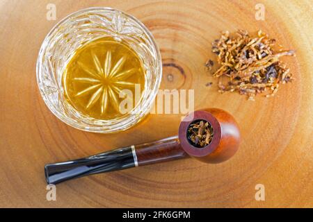 Bicchiere di whisky singolo scotch al malto accanto al classico miscelato tabacco aromatizzato su sfondo di legno luminoso Foto Stock
