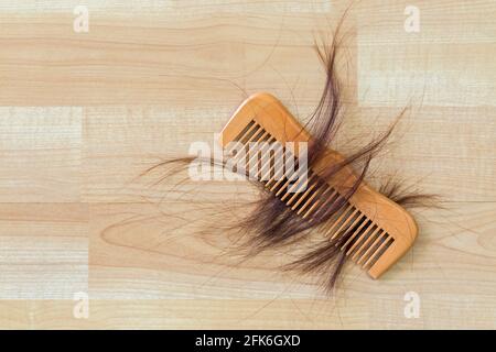 Molti capelli marroni su pettine di legno su pavimento di legno con copyspace. Concettuale per problema di perdita dei capelli Foto Stock