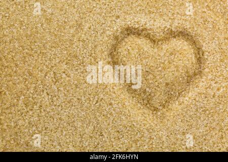 Vista dall'alto del cuore a forma di zucchero cristallino non sbiancato non raffinato di colore marrone cristallo. Foto concettuale per amore dolce Foto Stock