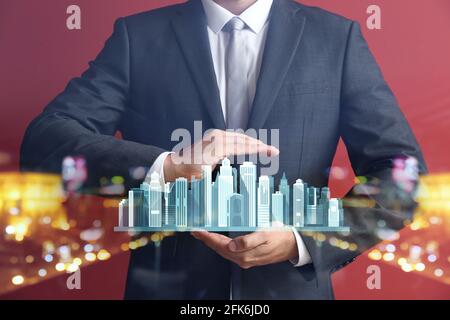 Agente immobiliare con proiezione digitale di edifici a colori sfondo Foto Stock