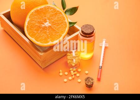 Composizione con pillole di vitamina C, ampolla, siringa e arance su sfondo colorato Foto Stock