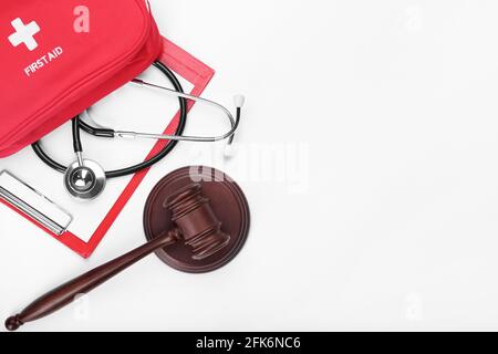Giudica gavel, stetoscopio, appunti e kit di pronto soccorso su sfondo bianco. Concetto di riforma sanitaria Foto Stock