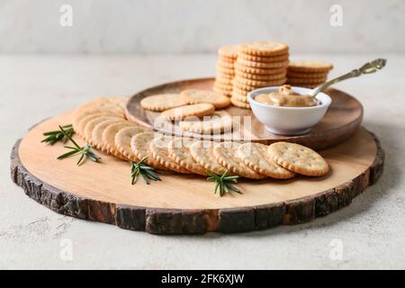 Piatto con gustosi cracker e burro di arachidi su sfondo chiaro Foto Stock