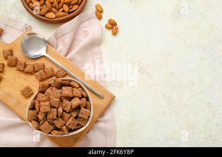 Ciotola con gustosi cuscini di mais e mandorle su sfondo chiaro Foto Stock