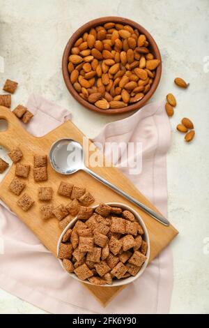 Ciotola con gustosi cuscini di mais e mandorle su sfondo chiaro Foto Stock