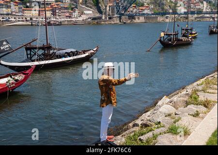 14.06.2018, Porto, Portogallo, Europa - Tourist prende un selfie sulla riva del fiume Douro con le tradizionali barche in legno chiamate Rabelos sullo sfondo. Foto Stock