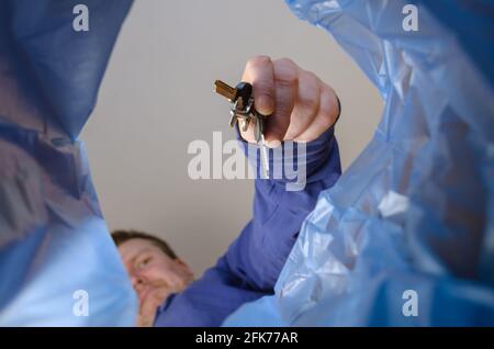 La mano getta le chiavi nel cestino. Un uomo tiene un mazzo di chiavi di porta sopra una lattiera di cestino. Vista dal basso. All'interno Foto Stock