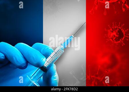 Francia Campagna di vaccinazione Covid-19. Una mano in un guanto di gomma blu contiene una siringa con vaccino del virus covid-19 davanti alla bandiera francese. Concetto di vaccinazione del coronavirus Foto Stock