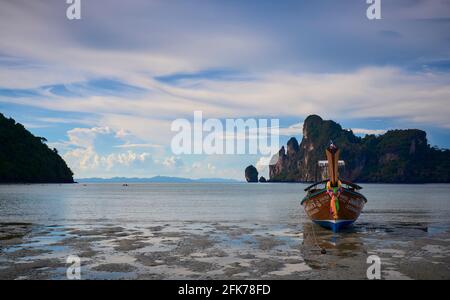 Una barca a coda lunga con coda lunga a bassa marea sulla spiaggia di Koh Dalum a Koh Phi Phi Don. Foto Stock