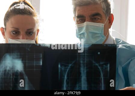 Giovane medico femminile con medico senior controlla un radiografia. Concetto di collaborazione tra medici giovani e medici esperti. Foto Stock