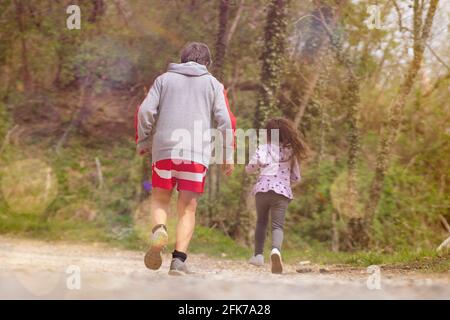 Nipote corre con suo nonno per aiutarlo a tornare in forma. Corsa al tramonto. Foto Stock