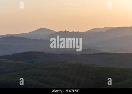 A stunning landscape view on an autumn morning of the hills of Tuscany with ploughed and green grass covered with beautiful undulating fields. The Foto Stock