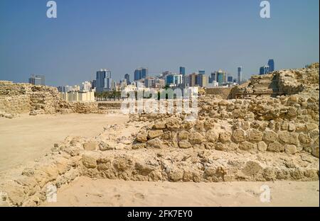 Vista mozzafiato del Forte del Bahrain o delle rovine della struttura Qall'at al-Bahrain con il moderno paesaggio urbano di Manama sullo sfondo, il Bahrain Foto Stock