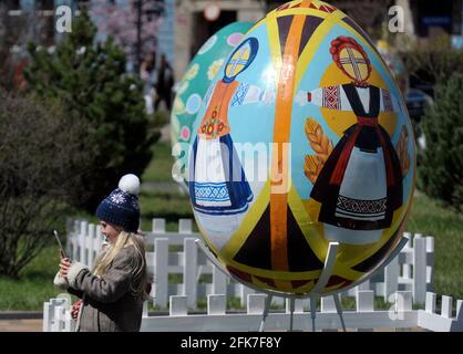 VINNYTSIA, UCRAINA - 28 APRILE 2021 - UNA ragazza si trova accanto a una delle pysankas 1.5m (3.2ft)-alto, uova di Pasqua ucraine, con Podillia folk ornam Foto Stock