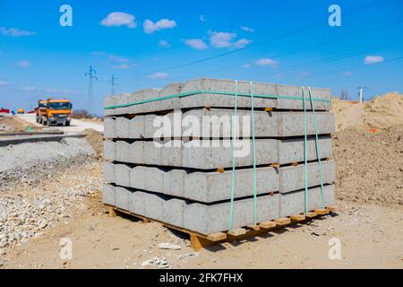 Pila di pietre di confine imballate per asfalto su pallet di legno in cantiere. Foto Stock
