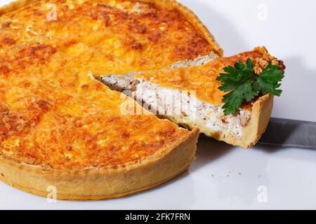 Presa della torta di funghi deliziosa con una spatola da cucina. Torta vegetale profumata su sfondo bianco. Couse in su. Foto Stock