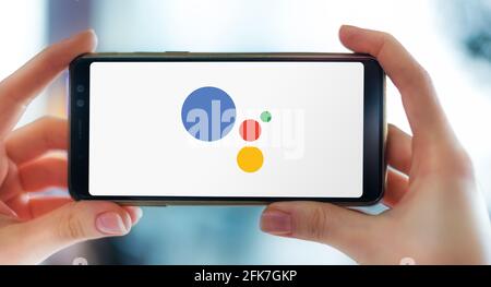 POZNAN, POL - Apr 25, 2021: Smartphone con mani che mostra il logo di Google Assistant, un assistente virtuale basato su intelligenza artificiale sviluppare Foto Stock