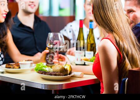 Amici o coppie di mangiare fast food e bere birra e vino in un American fast food diner Foto Stock