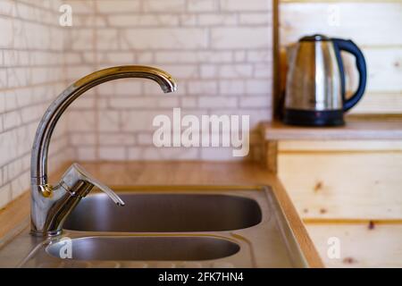 Primo piano di rubinetto e lavandino in cucina a casa. Dettaglio di una cucina leggera. Foto Stock