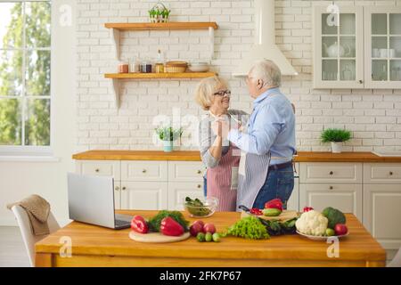 Coppia anziana amorosa che si diverte e ballano il valzer durante la cucina pasto sano insieme Foto Stock