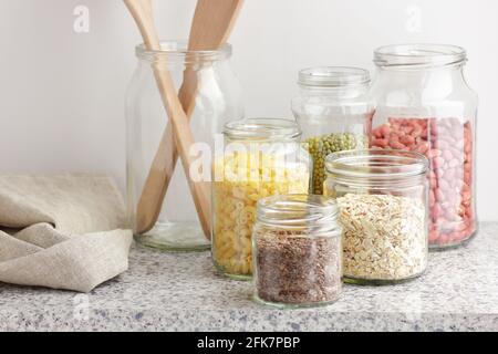 Varietà di cereali, cereali, pasta, semi in vasetti di vetro non cotti su fondo bianco della cucina, closeup, rifiuti zero, eco-friendly, alimentazione a dieta equilibrata, lui Foto Stock