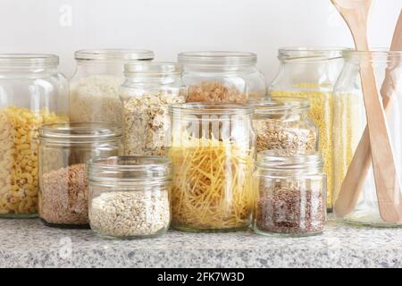 Varietà di cereali, cereali, pasta, semi in vasetti di vetro non cotti su fondo bianco della cucina, closeup, rifiuti zero, eco-friendly, alimentazione a dieta equilibrata, lui Foto Stock