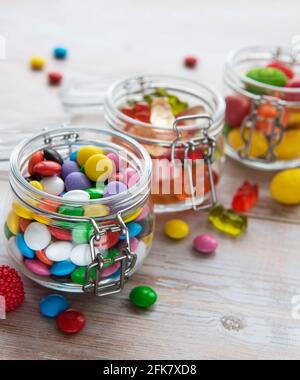 Caramelle colorate, gelatina e marmellata in vasi sul tavolo Foto Stock