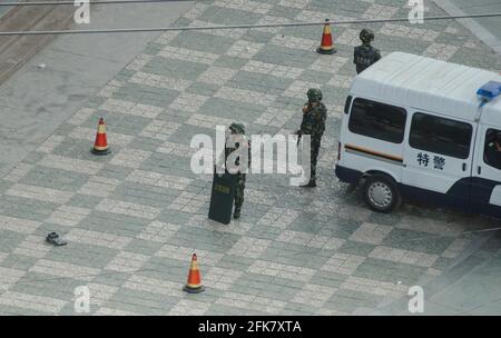 La polizia di sicurezza con scudi, batoni e armi da fuoco si trova accanto a un furgone di polizia che ha allestito un'obesità lungo una delle strade principali di Kashgar nel sud di Xinjiang, Cina, RPC. © Time-Snap Foto Stock