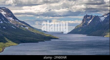 Le montagne innevate sorgono dalle fredde acque del fiordo norvegese Foto Stock