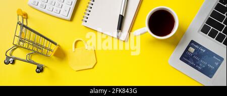 Concetto di shopping online. Vista dall'alto del concetto di design di acquisto della carta di credito con nota, calcolatrice e computer isolati su sfondo giallo del tavolo dell'ufficio Foto Stock