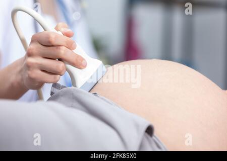 Vista ravvicinata del trasduttore a ultrasuoni sull'addome di una donna incinta. Ufficio di Ginecologia. Foto Stock