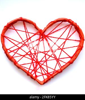 Un cuore di carta legato con fili rossi. Cuore su sfondo bianco. Foto Stock