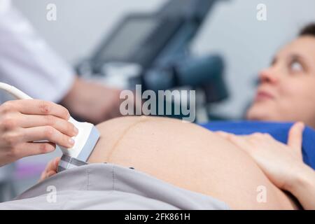 Vista ravvicinata del trasduttore a ultrasuoni sull'addome di una donna incinta. Ufficio di Ginecologia. Foto Stock